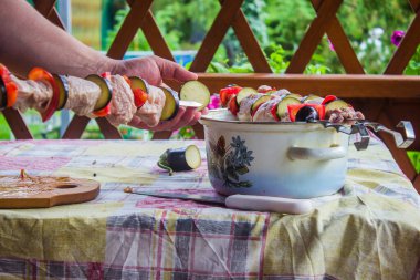 Et, domates ve patlıcan parçaları piknikte bir aşçının ellerinde şişlere dizilmişti.