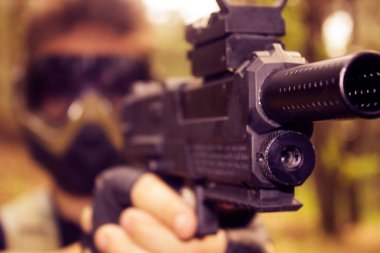 Siyah tabanca, maskeli genç bir özel kuvvetler askerinin elinde.