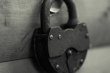 Eski demir menteşeli ahır eski kilidi, ahşap bir kapının üzerinde bir döngüyle kapandı.