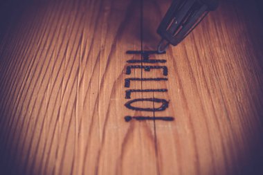 Tahta üzerinde bir insanın elindeki elektrikli ocağın iğnesi.