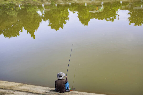 Man fishing along the river banks.