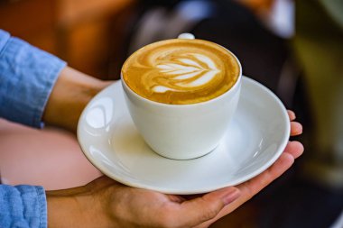 Kahve Kupası çiçek kahve Kupası ve kadın parmağında holding eller.