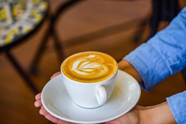 Kahve Kupası çiçek kahve Kupası ve kadın parmağında holding eller.