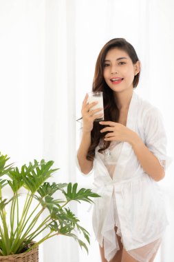 Elinde bir bardak süt tutan beyaz bir elbise giyen kadınlar.