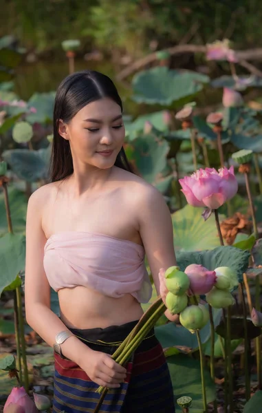 Uma mulher bonita em vestido tailandês fica em uma lagoa de lótus . — Fotografia de Stock