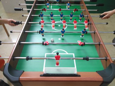 Çocuk ve bir tablo futbol oyunu oynarken bir bayan