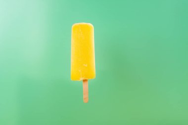 yellow popsicle on a light green background clipart