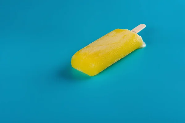 Widok Boczny Żółty Popsicle Zaczyna Przedzierać Się Niebieskim Tle — Zdjęcie stockowe