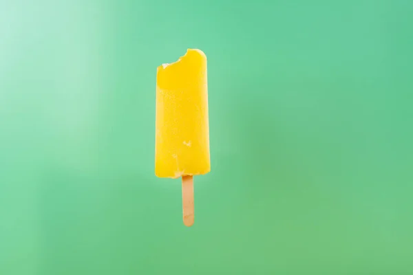 Picolé Amarelo Com Uma Mordida Fundo Verde Claro — Fotografia de Stock