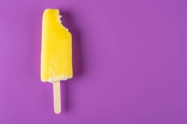 mor bir arka plan üzerinde bir ısırık ile sarı buzlu şeker