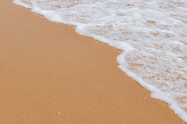 Kumlu bir sahilde yumuşak dalgalar