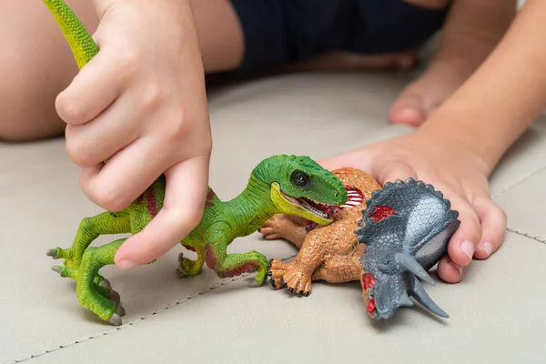 집에서 소파에 Velociraptor와 트리케라톱스 시체의 장난감을가지고 — 스톡 사진