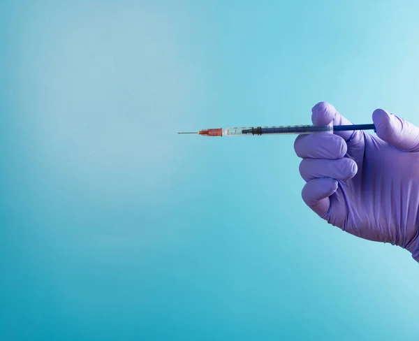 hand holding syringe medical injection on blue background