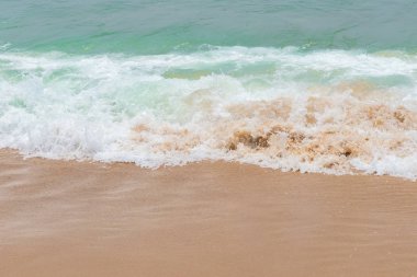 yumuşak kumlu bir plaj üzerinde bir okyanus dalgası