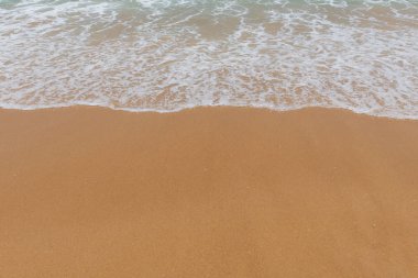 Kumlu bir sahilde yumuşak dalgalar