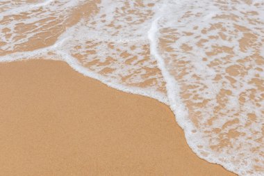 Kumlu bir sahilde yumuşak dalgalar