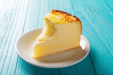 yan görünümü stüdyo çekimi ev yapımı peynir pasta bir ısırık ile mavi bir tabloda