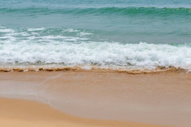 yumuşak kumlu bir plaj üzerinde bir okyanus dalgası