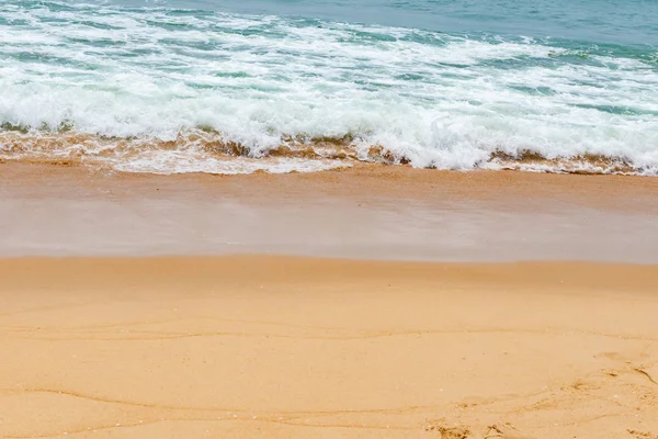 yumuşak kumlu bir plaj üzerinde bir okyanus dalgası