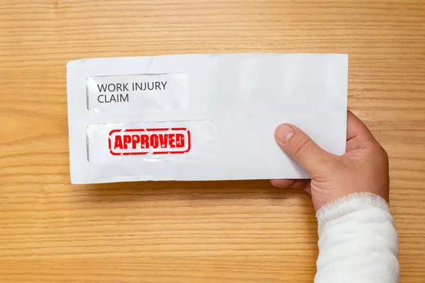 Wrapped Hand Holding Envelope Work Injury Claim Application Stamped Approved — Stock Photo, Image
