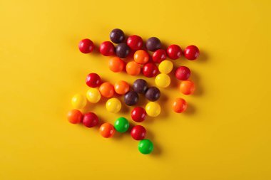 Stüdyo üstten görünüm renkli çikolata düğmeler sarı zemin üzerine vurdu.