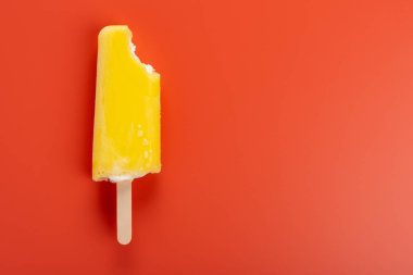 bir turuncu renk arka plan üzerinde bir ısırık ile sarı buzlu şeker