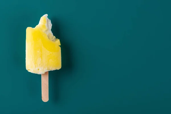 yellow popsicle with some bites on a navy blue background