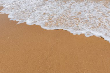 Kumlu bir sahilde yumuşak dalgalar