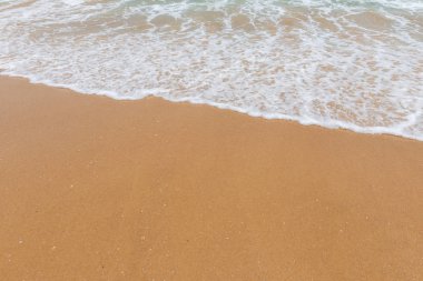 Kumlu bir sahilde yumuşak dalgalar