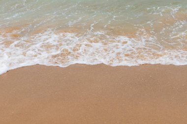 Kumlu bir sahilde yumuşak dalgalar