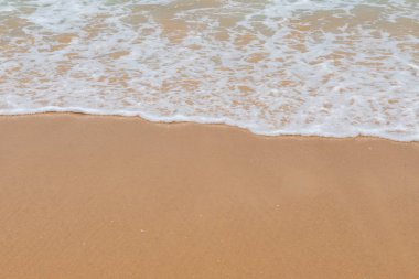 Kumlu bir sahilde yumuşak dalgalar