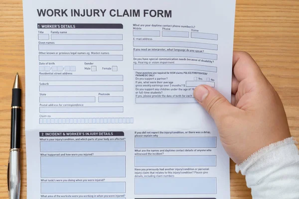 man with wrapped hand reading a work injury claim form