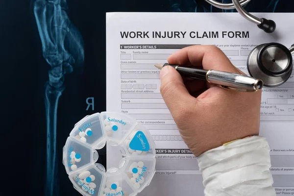 Man Filling Work Injury Claim Form Stethoscope Box Pills Top — Stock Photo, Image