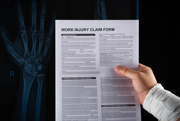 Studio Shot Man Reading Work Injury Claim Form Wrapped Hand — Stock Photo, Image