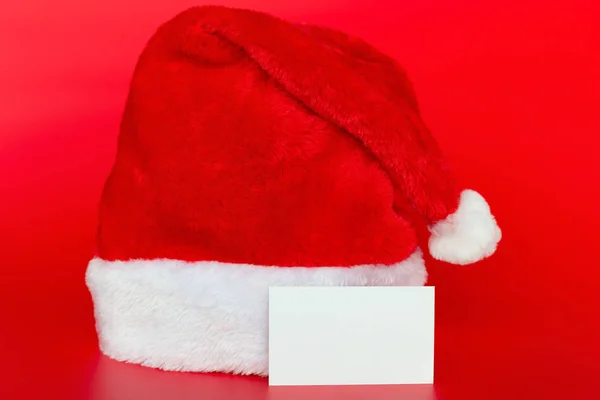 Sombrero Santa Claus Sobre Fondo Rojo Con Una Tarjeta Blanco — Foto de Stock