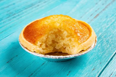 bir ısırık ile taze cocknut tart mavi ahşap arka plan üzerinde Kapat