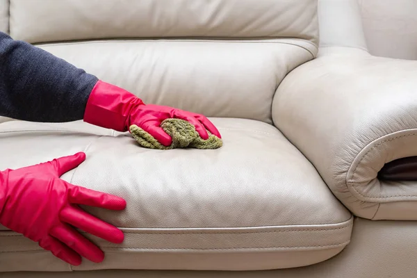 side view man cleaning leather sofa at home with wet towel