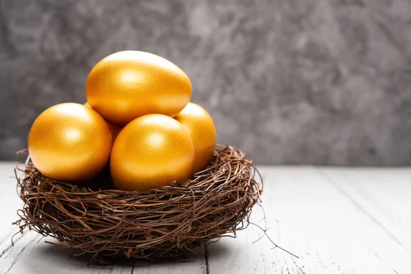 gold eggs on a nest on a white wood table