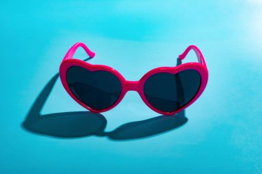 Kalp şekli güneş gözlüğü mavi zemin üzerine