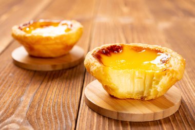 iki taze Portekizce yumurta tart ve ahşap bir masa bir ısırık ile bir adet
