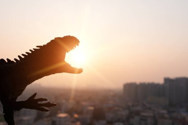 Silhouette Carnotaurus ve günbatımı zamanı binalarda