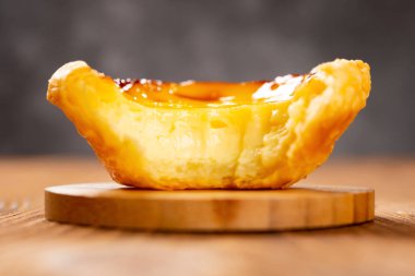 taze Portuguese yumurta bir ısırık ile tart bir ahşap masa yakın yukarı