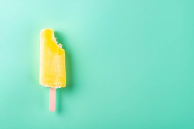 Açık mavi arka planda bir ısırık ile sarı dondurma