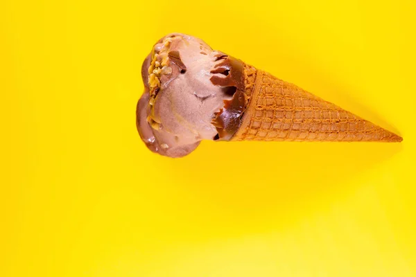 top view chocolate flavor ice cream cone in a melting process on yellow background