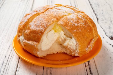 ahşap masada bir ısırık ile içinde krem ile yan görünüm ekmek