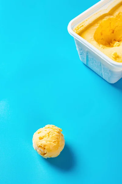top view mango flavor ice cream ball and the box on blue background