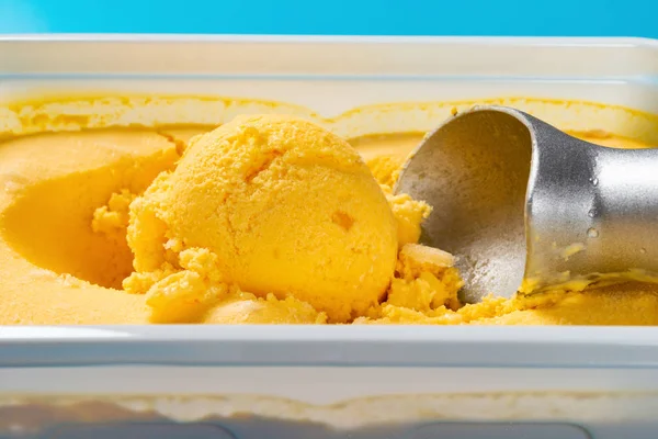 mango flavor ice cream ball and spoon close up