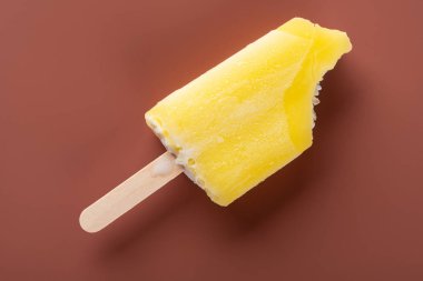 Kahverengi arka planda ısırık izleri olan sarı buzlu şeker.