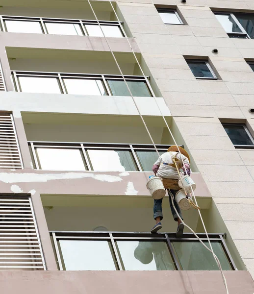 Trabajador colgando con cuerdas y pintando la parte exterior de un highris —  Fotos de Stock