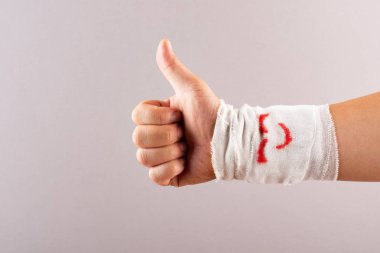 başparmak yukarıya gülümseyen yüzü sarılı bir el tarafından postive jesti